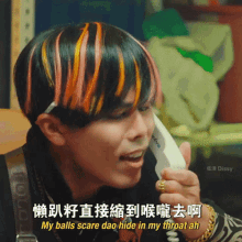 a man with colorful hair is talking on a phone with chinese writing on it