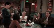 a group of people are sitting at a table in a restaurant with an exit sign in the background