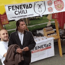 two men are standing in front of a fenevad chili stand