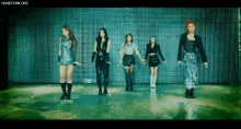 a group of girls are standing in front of a wall and holding hands