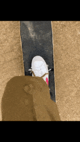 a person 's foot is on a skateboard with a white shoe