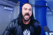 a man with long hair and a beard is wearing a black shirt that has flames on it