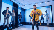 a group of people are dancing in a room with a man in a yellow jacket that says just do it