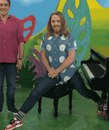 a man in a polka dot shirt sits on a piano bench