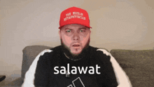 a man wearing a red hat that says the muslim methaphysician is sitting on a couch