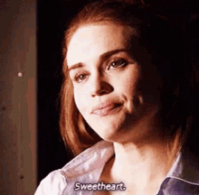 a woman in a purple shirt is smiling and saying sweetheart .