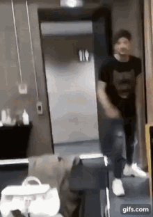 a man in a black shirt is standing in a hallway .