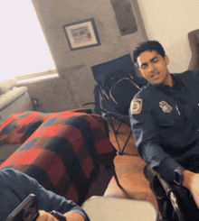 a man in a police uniform sits in a chair in front of a bed