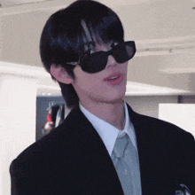 a young man wearing sunglasses and a suit and tie