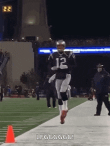 a football player is running on a field with a cone in the foreground .