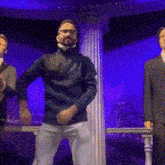 a man in a blue sweater is dancing with two other men in suits .