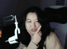 a woman is sitting in front of a microphone with her hand on her chin .