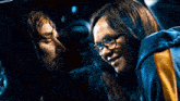 a man and a woman are looking at each other in a car . the woman is wearing glasses .
