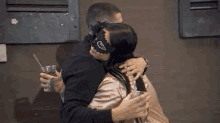 a man and a woman are kissing in front of a building while the woman is wearing a mask .