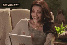 a woman is sitting on a couch looking at a tablet computer .