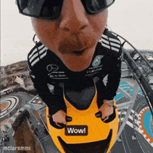 a man wearing sunglasses and a mercedes shirt is riding a yellow motorcycle with a wow sticker on the front