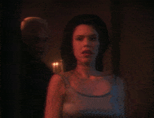 a man and a woman in a dark room with candles in the background