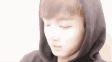 a young man wearing a black hoodie with his eyes closed .