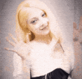 a woman with blonde hair is waving her hand in the air