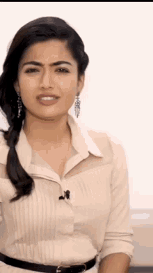 a woman wearing a white shirt and earrings looks at the camera
