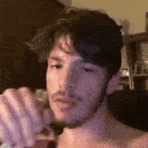 a man with a beard is holding a glass in front of his face .