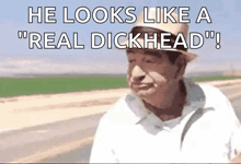 a man in a hat is standing in front of a field with the words `` he looks like a `` real dickhead '' .