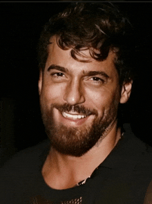 a man with a beard and curly hair is smiling for the camera