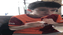 a young boy wearing an orange shirt with the letter ea on it
