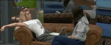 two women are sitting on a couch with a laptop on it .