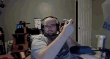 a man wearing headphones and glasses is holding a video game controller