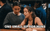 two women are sitting at a table and one of them is saying one small sip for nuns