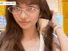a close up of a woman wearing glasses with the number 27 on the bottom right