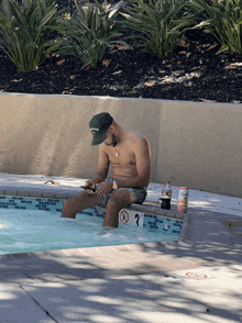 a man sits on the edge of a pool wearing a hat that says delta on it
