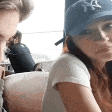 a woman wearing a new york yankees hat is sitting next to a man