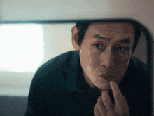 a man looks at himself in a mirror with his finger in his mouth