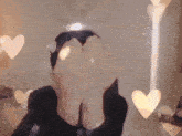 a person covering their eyes with their hands and hearts behind them