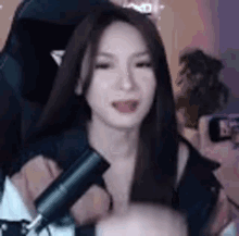 a woman is sitting in a chair holding a microphone in front of her face .