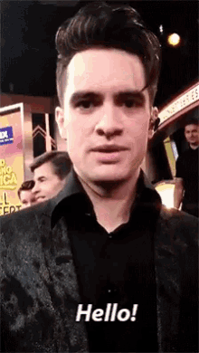 a man in a black suit says hello in a video
