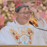 a man with glasses and a red hat stands in front of a podium with the letters lje on the bottom right