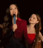 two women are standing next to each other with one holding a microphone