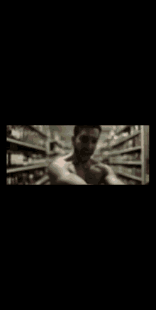 a man without a shirt is standing in a store aisle