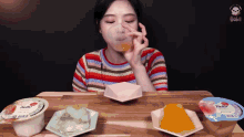 a woman drinking orange juice from a glass while sitting at a table