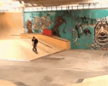 a person riding a skateboard in front of a wall with graffiti on it