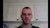 a man with a beard is standing in front of a white cabinet