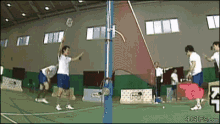 a group of people are playing a game of badminton in a gym sponsored by 4gifs.com