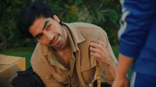 a man is sitting on a bench holding a cane and smiling .