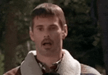 a man with a beard is making a funny face while wearing a jacket and tie .