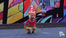 a man wearing a party hat is holding balloons in front of a wall with jib job written on it