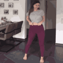 a woman in purple pants is standing on a yoga mat in a living room