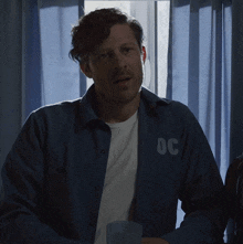 a man wearing a blue shirt with the letters oc on the back
